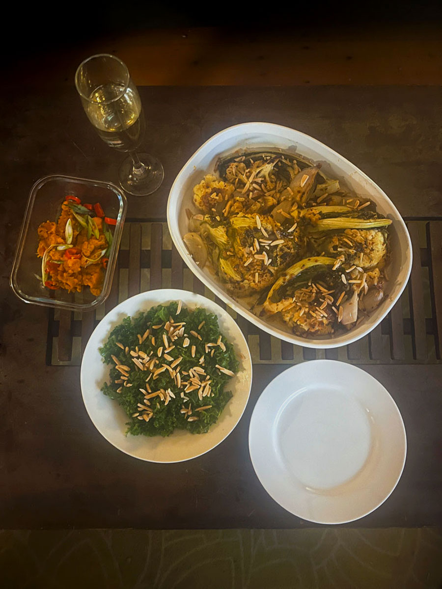 Four dishes of food and a flute of wine on a dark wooden table