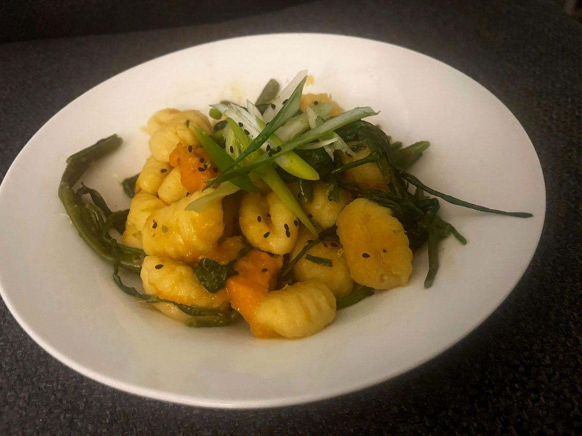 A bowl of gnocchi with green vegetables