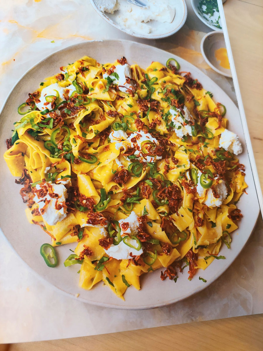 An open cookbook showing a photograph of saffron and tagliatelle in a cookbook