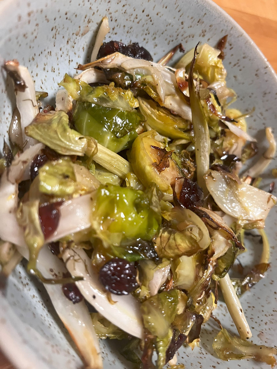 closeup shot of baked salad with shredded green and white vegetables and a red dressing in a blue speckled bowl