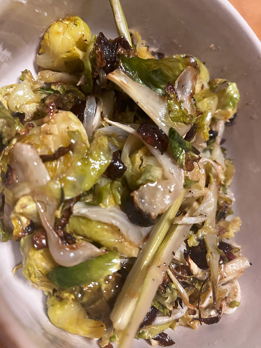 closeup shot of baked glossy salad with shredded white and green vegetables with a red dressing in a beige bowl
