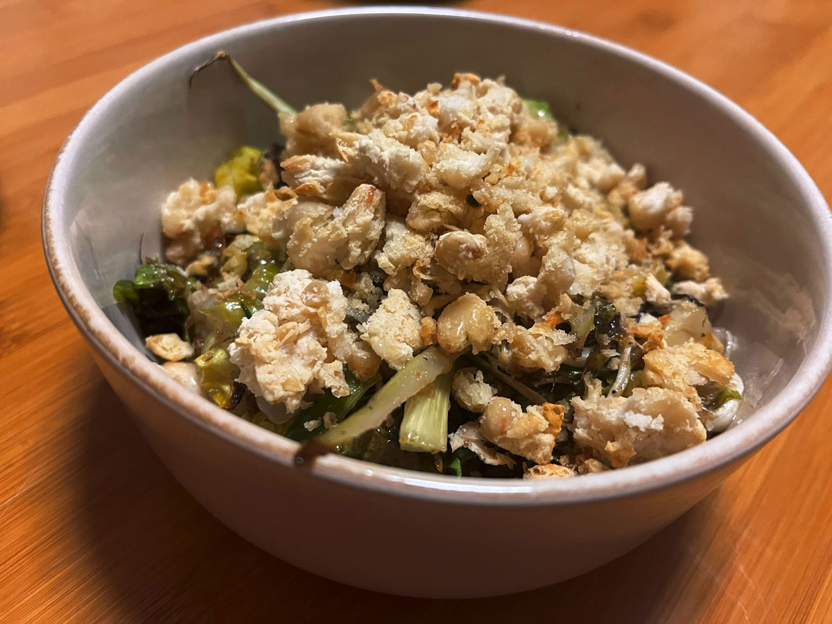 photo of bowl of baked salad, covered in white bean crumble in a beige bowl