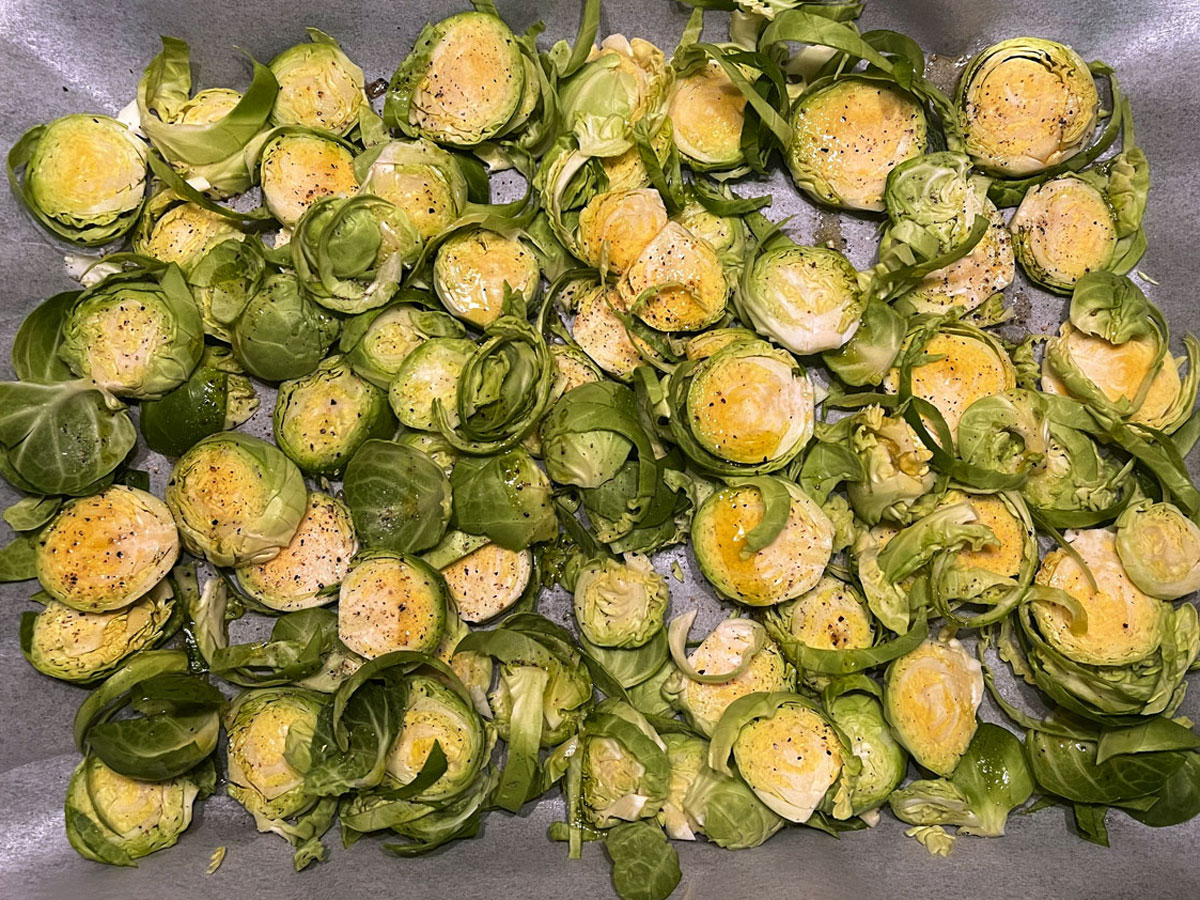sliced brussels sprouts on baking tray lined with baking paper, drizzled with olive oil and seasoned with salt and pepper