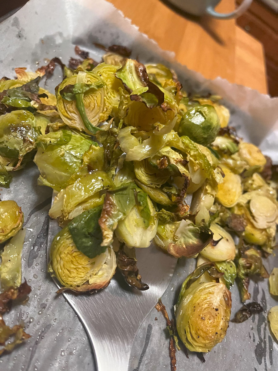 baked slices of browned brussels sprouts lifted by a metal spatula off tray