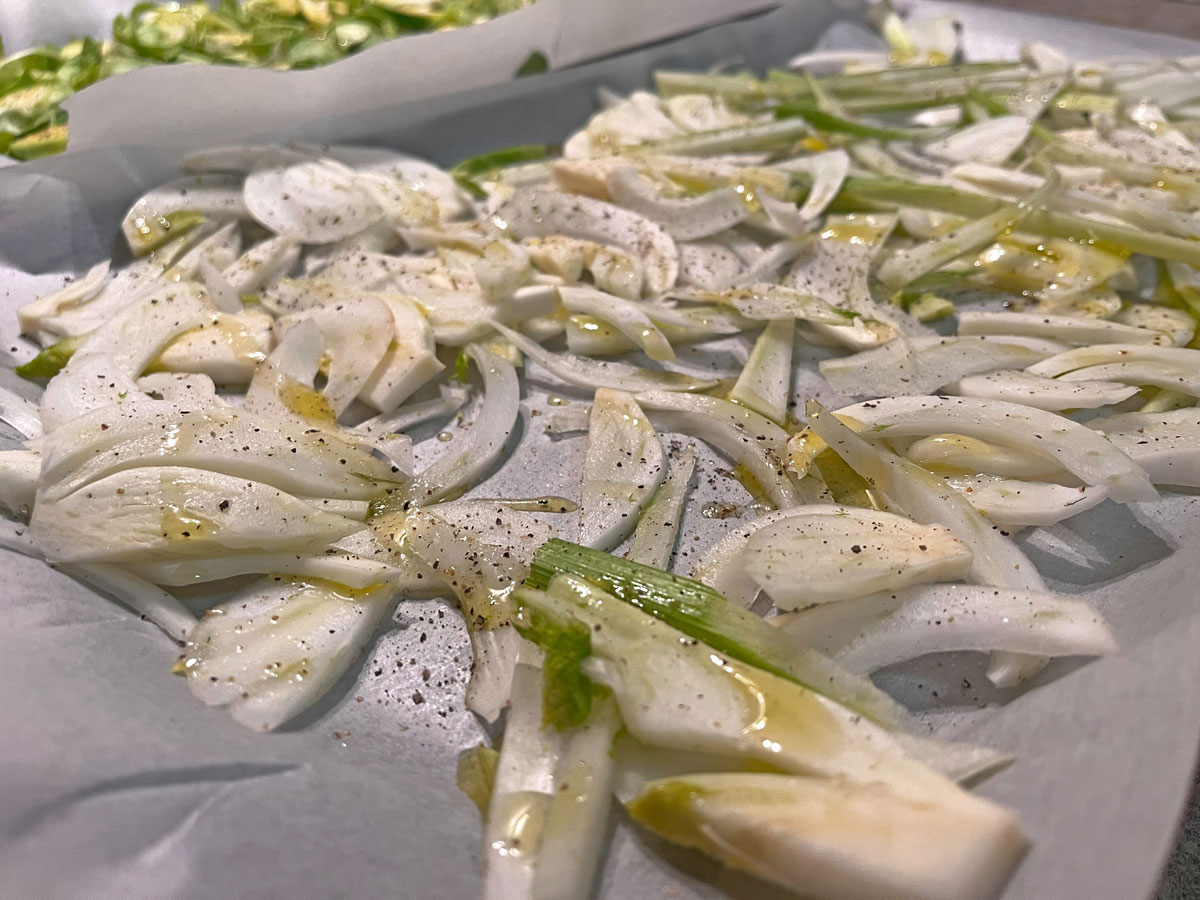 sliced raw fennel on baking tray lined with baking paper, drizzled with olive oil and seasoned with salt and pepper