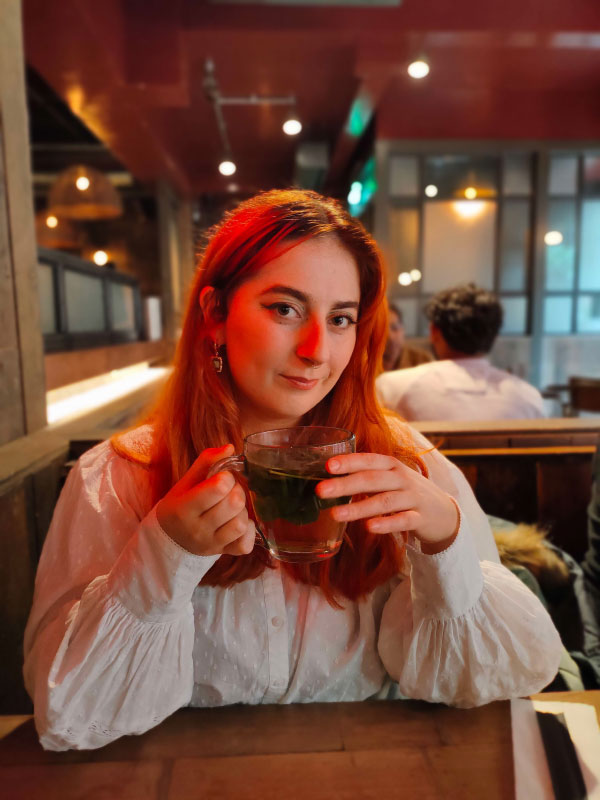 A photograph of the author, Kitty, seated at a restaurant holding a glass of tea